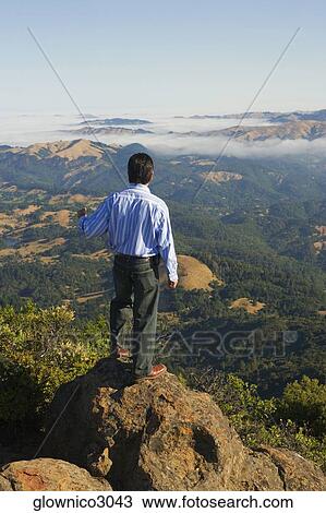 High angle view of a man standing on a hilltop View Large Photo Image Stock Image - High angle view of a man standing on a hilltop. Fotosearch