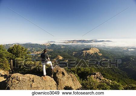 High angle view of a man standing on a hilltop View Large Photo Image Stock Photo - High angle view of a man standing on a hilltop. Fotosearch