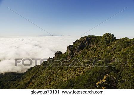 High angle view of clouds around a hill View Large Photo Image Stock Image - High angle view of clouds around a hill. Fotosearch