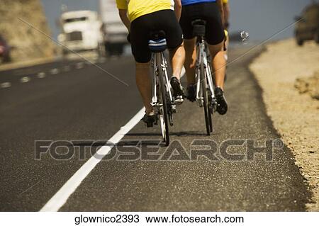 Low section view of two people riding cycles on a road View Large Photo Image Stock Image - Low section view of two people riding cycles on a road. Fotosearch