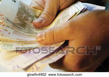 Man holding several Euro bank notes, close-up View Large Photo Image Stock Image - Man holding several Euro bank notes, close-up. Fotosearch
