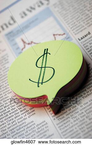 Stock Photo - Notepad with dollar sign on it, on top of business section of newspaper, close-up. Fotosearch