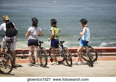 Rear view of a group of cyclists looking at the Ocean View Large Photo Image Stock Photo - Rear view of a group of cyclists looking at the Ocean. Fotosearch