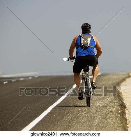 Rear view of a man riding a cycle View Large Photo Image Stock Image - Rear view of a man riding a cycle. Fotosearch