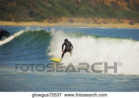 Stock Photo - Rear view of a person surfing. Fotosearch
