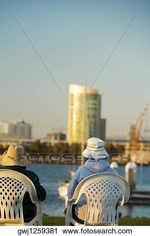 Rear view of two people sitting on a waterfront, San Diego Bay, San Diego, California, USA View Large Photo Image Stock Image - Rear view of two people sitting on a waterfront, San Diego Bay, San Diego, California, USA. Fotosearch