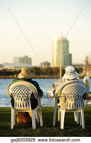 Rear view of two people sitting on a waterfront, San Diego Bay, San Diego, California, USA View Large Photo Image Stock Photo - Rear view of two people sitting on a waterfront, San Diego Bay, San Diego, California, USA. Fotosearch
