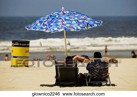 Rear view of two people sitting on the beach View Large Photo Image Stock Photograph - Rear view of two people sitting on the beach. Fotosearch