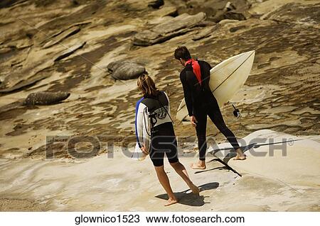 Rear view of two surfers walking on the beach View Large Photo Image Stock Image - Rear view of two surfers walking on the beach. Fotosearch