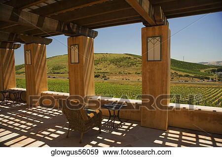 Stock Photo - Table and a chair in a trellised corridor. Fotosearch