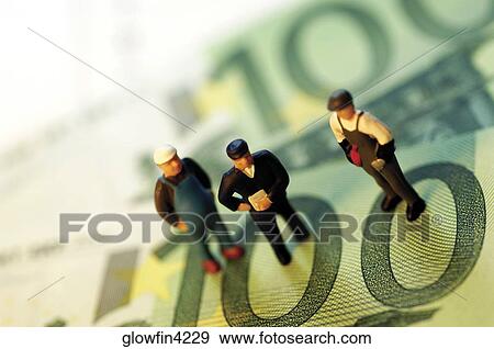 Three toy men standing on top of paper currency, close-up View Large Photo Image Stock Photo - Three toy men standing on top of paper currency, close-up. Fotosearch