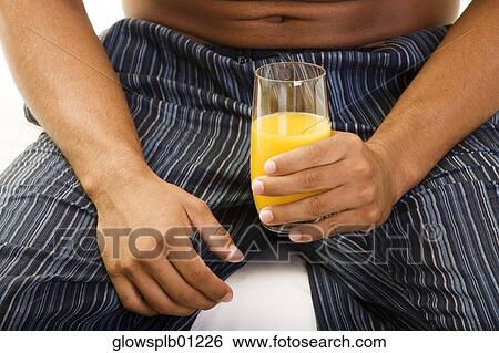 Torso of man sitting with glass of orange juice View Large Photo Image Stock Photograph - Torso of man sitting with glass of orange juice. Fotosearch