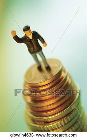 Stock Image - Toy man on top of stack of coins. Fotosearch