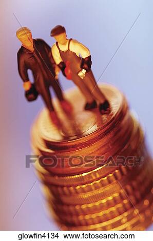 Two toy men on top of stack of coins, close-up View Large Photo Image Picture - Two toy men on top of stack of coins, close-up. Fotosearch