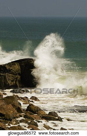Stock Image - Waves crashing against a rock formation in the sea. Fotosearch