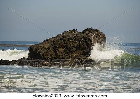 Waves crashing against a rock formation in the sea View Large Photo Image Stock Photo - Waves crashing against a rock formation in the sea. Fotosearch