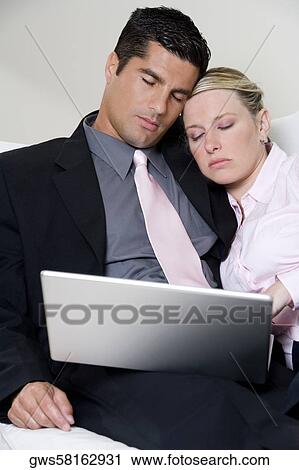 Businessman and a businesswoman sleeping in front of a laptop View Large Photo Image Stock Image - Businessman and a businesswoman sleeping in front of a laptop. Fotosearch