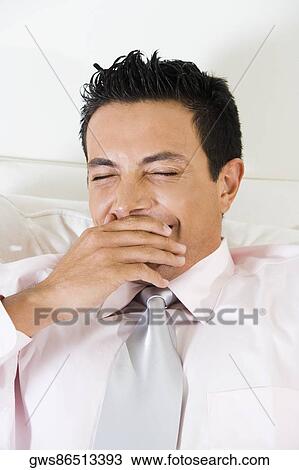 Businessman covering his mouth with his hand while yawning View Large Photo Image Stock Image - Businessman covering his mouth with his hand while yawning. Fotosearch