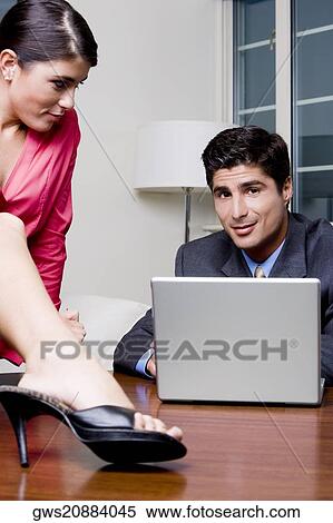 Stock Photography - Businessman sitting in front of a laptop with a businesswoman looking at him. Fotosearch