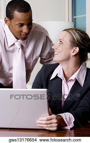 Picture - Close-up of a businessman and a businesswoman in front of a laptop. Fotosearch