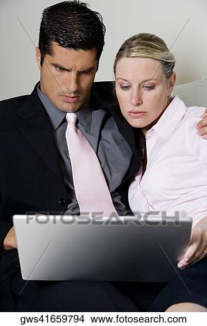 Close-up of a businessman and a businesswoman using a laptop View Large Photo Image Picture - Close-up of a businessman and a businesswoman using a laptop. Fotosearch