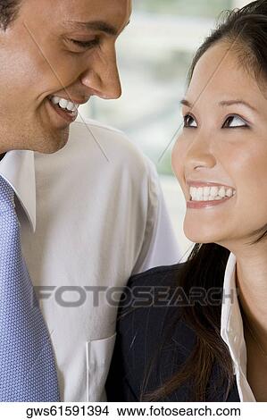 Picture - Close-up of a businessman and a businesswoman smiling. Fotosearch