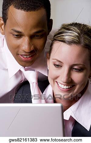 Close-up of a businessman and a businesswoman smiling in front of a laptop View Large Photo Image Stock Image - Close-up of a businessman and a businesswoman smiling in front of a laptop. Fotosearch