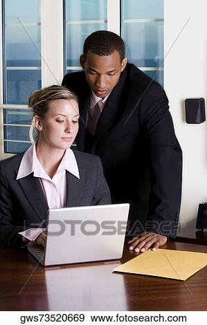 Close-up of a businessman and a businesswoman looking at a laptop View Large Photo Image Stock Photo - Close-up of a businessman and a businesswoman looking at a laptop. Fotosearch