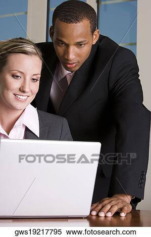 Stock Photography - Close-up of a businessman and a businesswoman looking at a laptop. Fotosearch