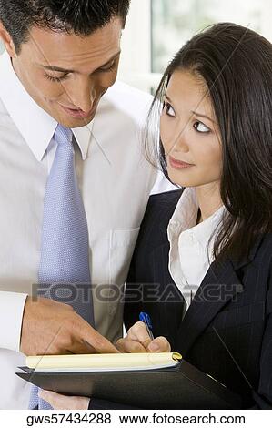 Stock Photo - Close-up of a businessman dictating notes to his secretary. Fotosearch
