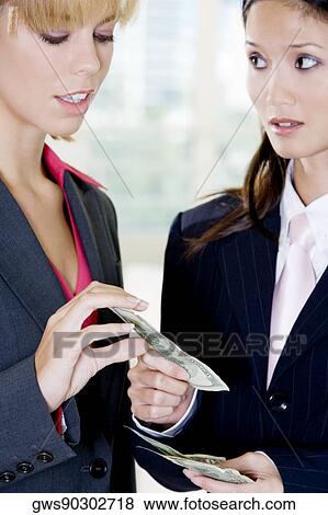 Close-up of a businesswoman giving a dollar bill to another businesswoman View Large Photo Image Stock Photo - Close-up of a businesswoman giving a dollar bill to another businesswoman. Fotosearch