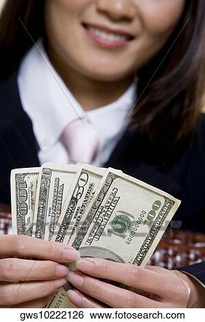 Close-up of a businesswoman holding one hundred dollar bills View Large Photo Image Stock Photograph - Close-up of a businesswoman holding one hundred dollar bills. Fotosearch