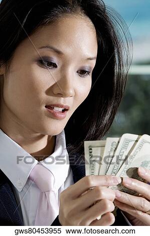 Stock Photography - Close-up of a businesswoman holding American dollar bills. Fotosearch