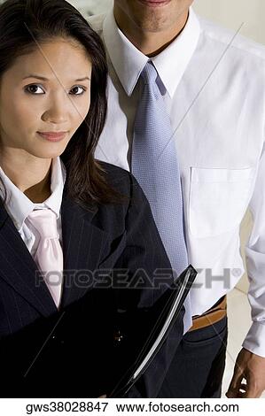 Close-up of a businesswoman with a businessman standing behind her View Large Photo Image Stock Photo - Close-up of a businesswoman with a businessman standing behind her. Fotosearch