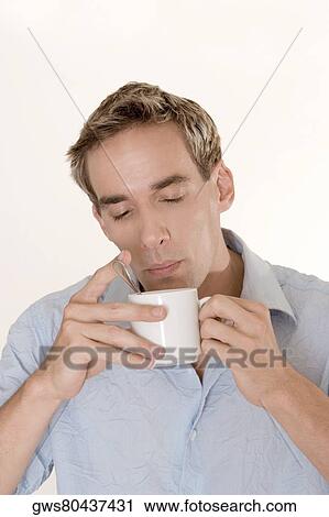 Stock Image - Close-up of a mid adult man blowing into a cup. Fotosearch