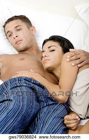 Close-up of a young couple lying on a bed View Large Photo Image Picture - Close-up of a young couple lying on a bed. Fotosearch