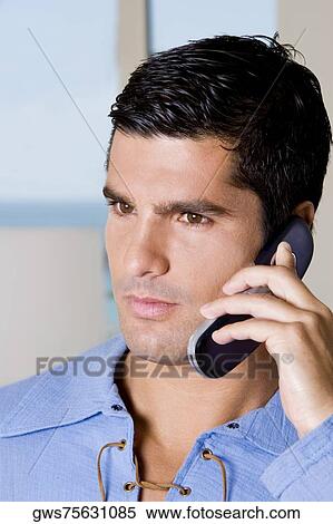 Close-up of a young man talking on a mobile phone View Large Photo Image Stock Photography - Close-up of a young man talking on a mobile phone. Fotosearch