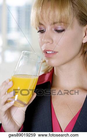 Close-up of a young woman holding a glass of orange juice View Large Photo Image Stock Photo - Close-up of a young woman holding a glass of orange juice. Fotosearch