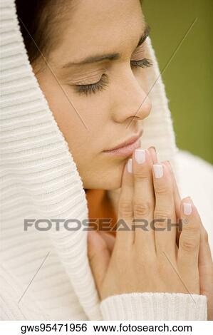 Close-up of a young woman praying View Large Photo Image Stock Photograph - Close-up of a young woman praying. Fotosearch
