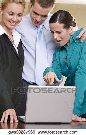 Close-up of two businesswomen and a businessman looking at a laptop View Large Photo Image Stock Image - Close-up of two businesswomen and a businessman looking at a laptop. Fotosearch