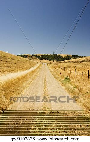 Dirt road passing through arid landscape View Large Photo Image Stock Photograph - Dirt road passing through arid landscape. Fotosearch