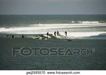 Stock Image - Distant view of a group of people surfing, Malibu, California, USA. Fotosearch