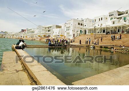 Stock Photograph - Group of people performing prayers along a lake, Holy Lake, Pushkar, Rajasthan, India. Fotosearch