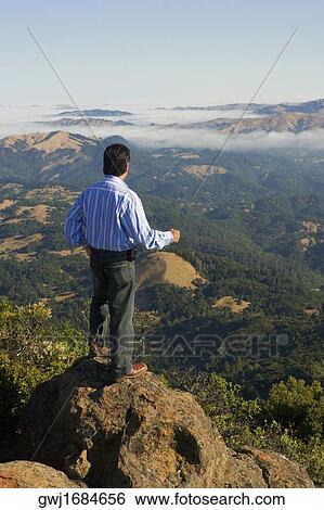 High angle view of a man standing on a hilltop View Large Photo Image Stock Photograph - High angle view of a man standing on a hilltop. Fotosearch