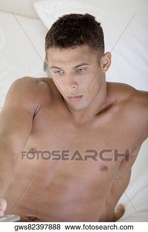 High angle view of a young man holding a remote control View Large Photo Image Stock Photo - High angle view of a young man holding a remote control. Fotosearch