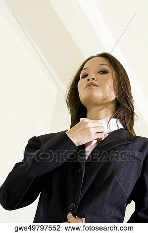 Stock Image - Low angle view of a businesswoman adjusting her tie. Fotosearch