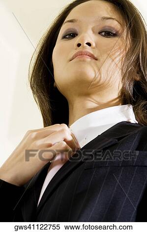 Stock Photography - Low angle view of a businesswoman adjusting her tie. Fotosearch