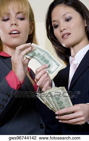 Low angle view of two businesswomen holding American paper currency View Large Photo Image Stock Image - Low angle view of two businesswomen holding American paper currency. Fotosearch
