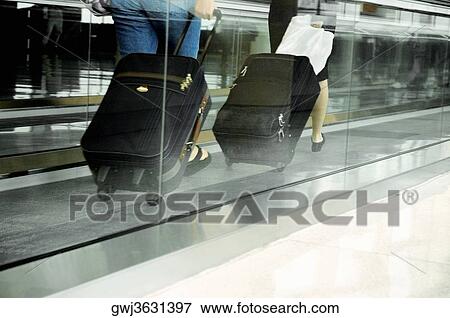 Low section view of two people with luggage on an escalator View Large Photo Image Stock Photo - Low section view of two people with luggage on an escalator. Fotosearch
