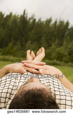 Stock Image - Mid adult man lying on the grass. Fotosearch